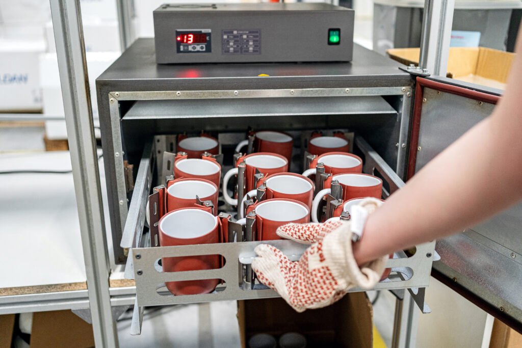 Sublimation printing process for custom mugs at Snapwear – mugs curing in a heat press chamber.